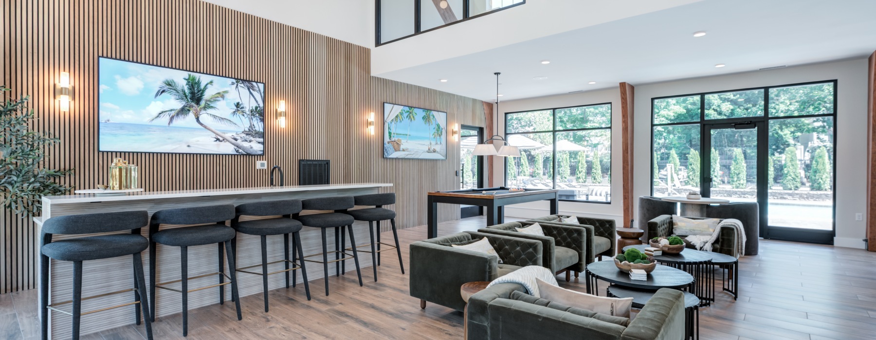 Elegant resident clubroom with modern lounge seating, a community bar, and cozy fireplace at Brookside Wilton in CT—schedule a tour to see our luxury amenities in person