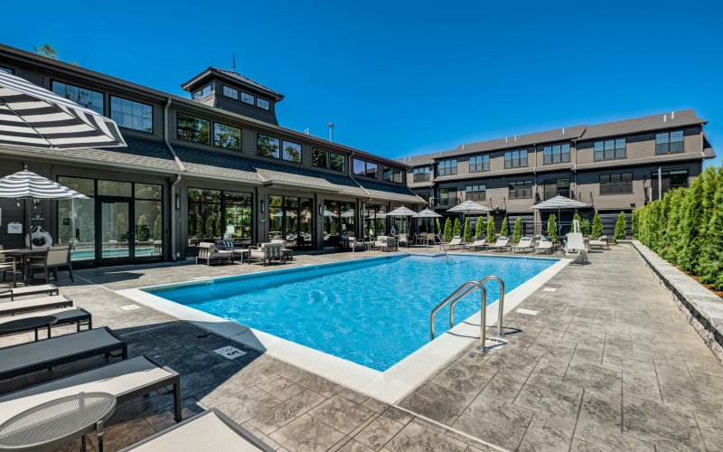 Sparkling resort-style outdoor swimming pool and lounge area with the luxury apartment building in the background at Brookside Wilton in CT