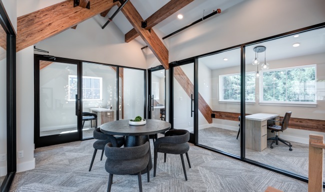 Modern resident coworking lounge with shared workspace table, seating, and glass doors at Brookside Wilton in Connecticut