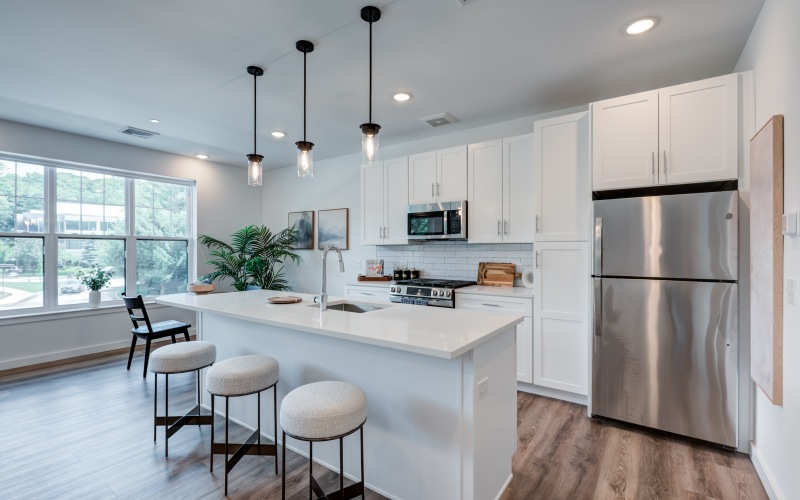 Modern open-concept kitchen with stainless steel appliances, a large island, and quartz countertops in a model apartment at Brookside Wilton in CT